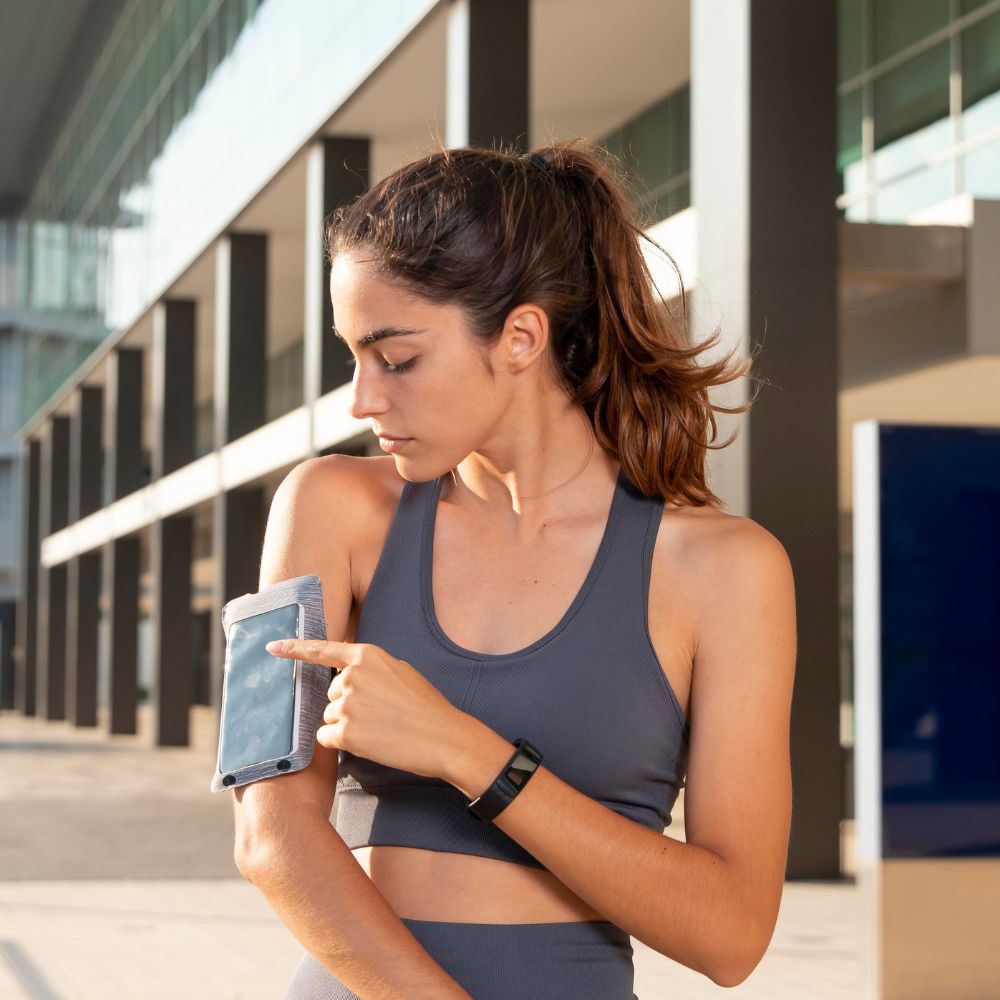 Female runner checking phone armband tracker during outdoor workout